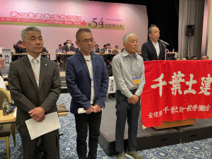 壇上で報告する津島英一さん（坪井分会）と同じく従事した布施裕一さん（薬園台分会）